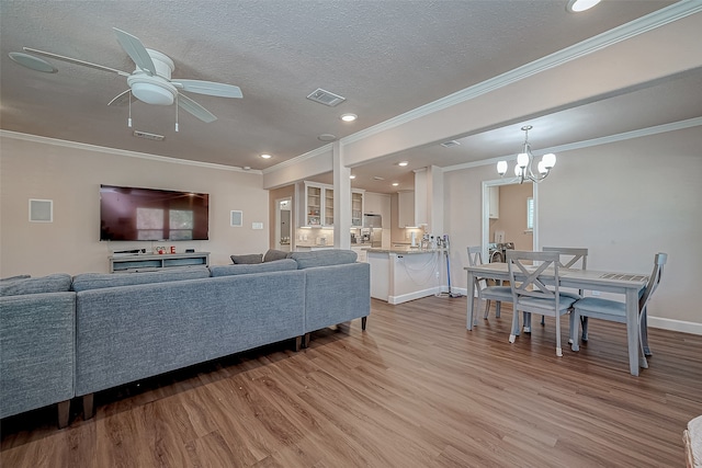 living room featuring a textured ceiling, ceiling fan with notable chandelier, light hardwood / wood-style floors, and crown molding