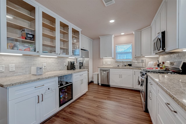 kitchen featuring white cabinets, appliances with stainless steel finishes, backsplash, and light hardwood / wood-style floors