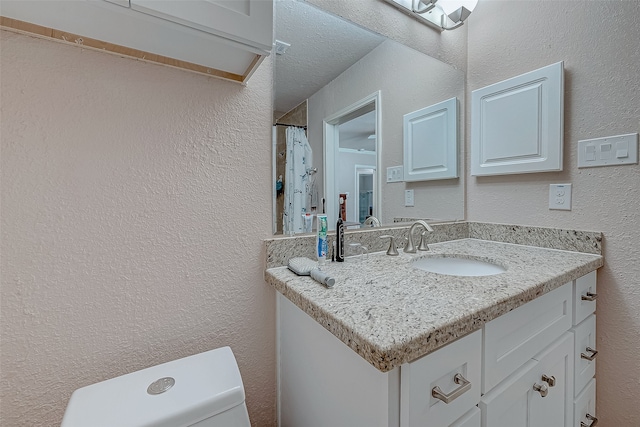 bathroom with vanity, toilet, and a textured ceiling