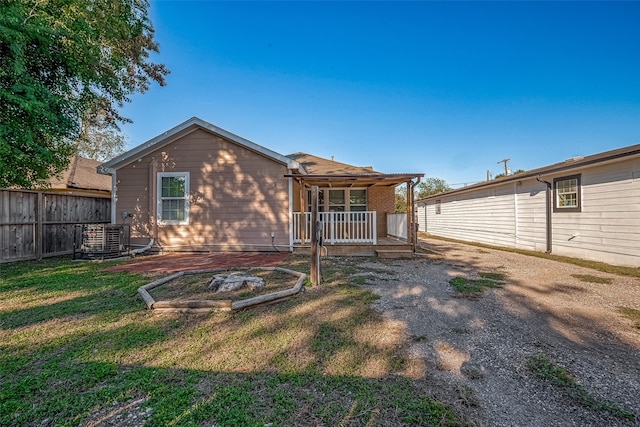 back of property with a porch, a yard, and central air condition unit