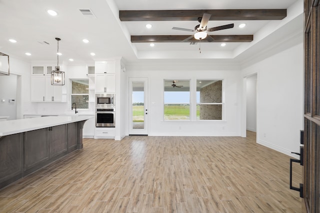 unfurnished living room with beamed ceiling, light hardwood / wood-style flooring, ceiling fan, and sink