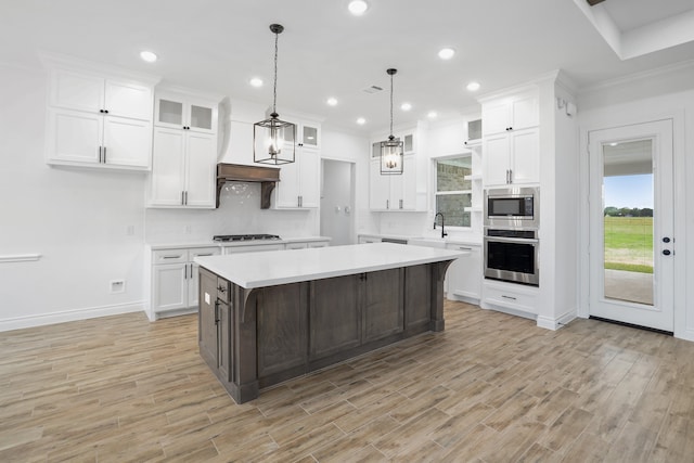 kitchen with hanging light fixtures, light hardwood / wood-style floors, a kitchen island, white cabinetry, and stainless steel appliances