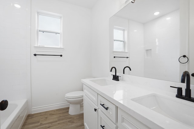 bathroom featuring a wealth of natural light, hardwood / wood-style floors, vanity, and toilet