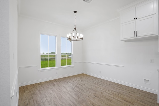 unfurnished room with light hardwood / wood-style floors, crown molding, and an inviting chandelier