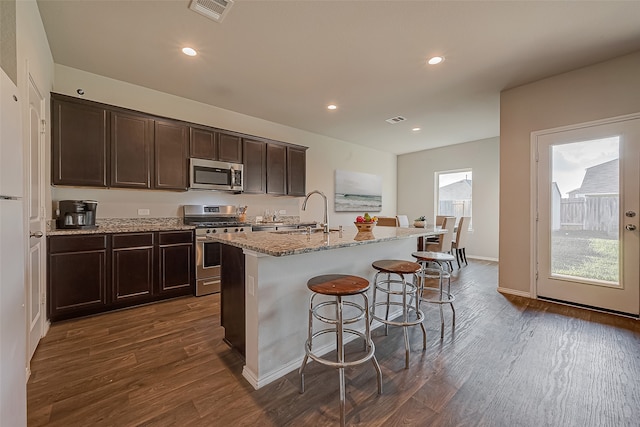 kitchen with sink, dark hardwood / wood-style flooring, a kitchen island with sink, dark brown cabinets, and appliances with stainless steel finishes