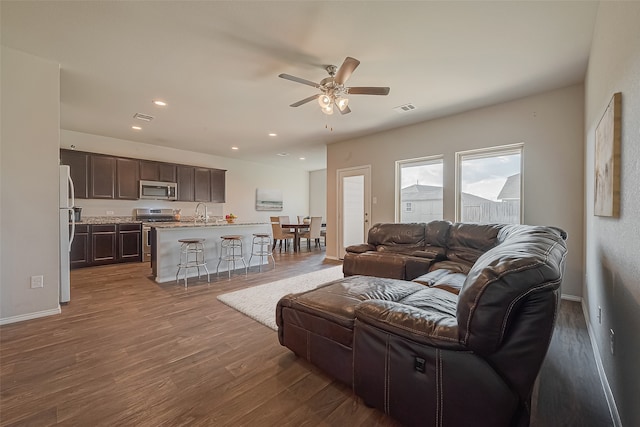 living room featuring ceiling fan, hardwood / wood-style floors, and sink