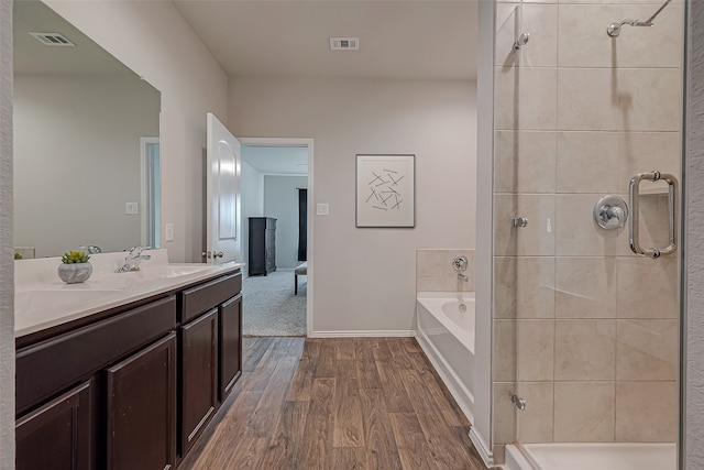 bathroom with hardwood / wood-style floors, vanity, and shower with separate bathtub