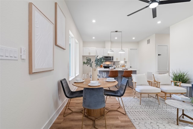 dining area with light hardwood / wood-style floors, ceiling fan, and sink