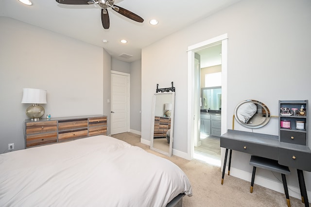 bedroom with ceiling fan, light colored carpet, and ensuite bathroom