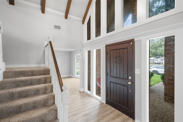 foyer entrance featuring beam ceiling, crown molding, high vaulted ceiling, and wood-type flooring