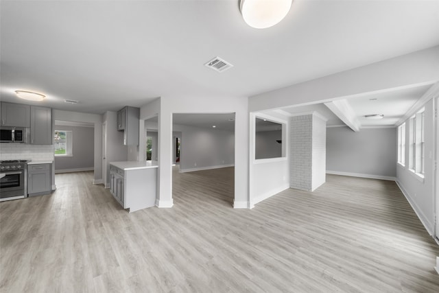 kitchen featuring beamed ceiling, backsplash, gray cabinets, appliances with stainless steel finishes, and light wood-type flooring