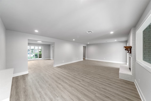 unfurnished living room with a fireplace and light wood-type flooring