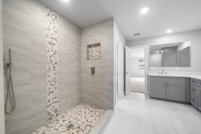 bathroom with a tile shower, vanity, and tile patterned floors