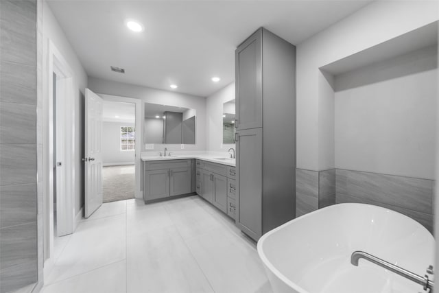 bathroom with vanity, tile patterned floors, tile walls, and a tub