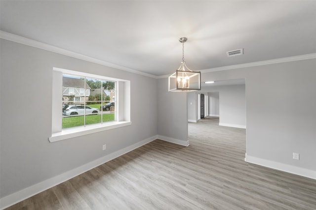 empty room with crown molding, a notable chandelier, and hardwood / wood-style flooring