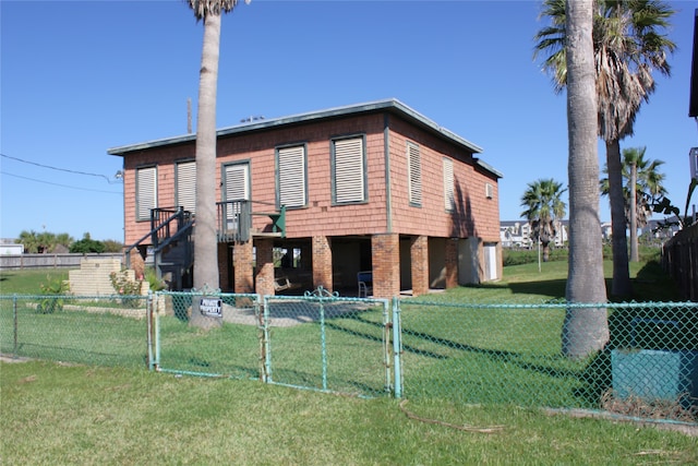 back of property featuring a yard, brick siding, fence private yard, and a gate