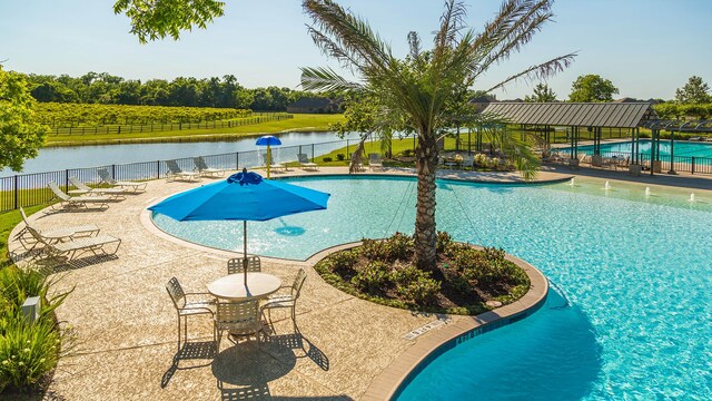 view of swimming pool featuring a water view and a patio area