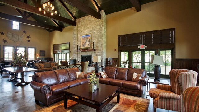 living room with a fireplace, wooden walls, high vaulted ceiling, beamed ceiling, and a chandelier