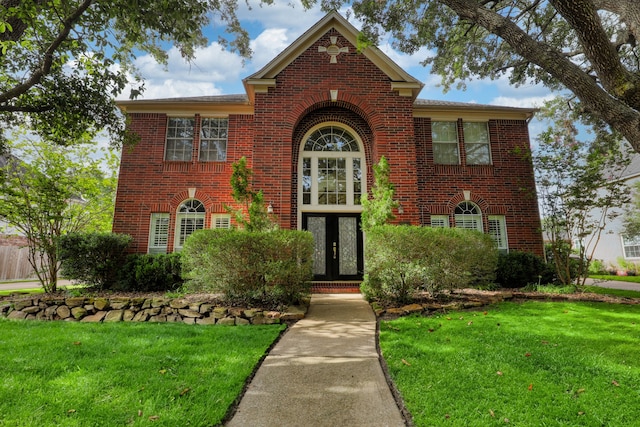 view of front of property featuring a front yard and french doors