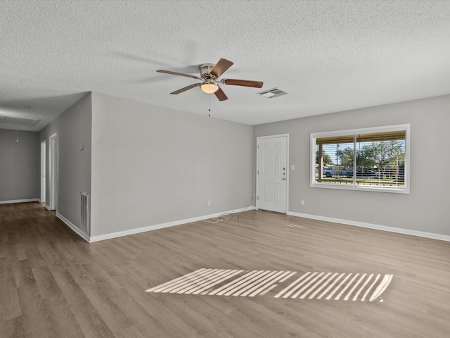 empty room featuring a textured ceiling, light hardwood / wood-style flooring, and ceiling fan