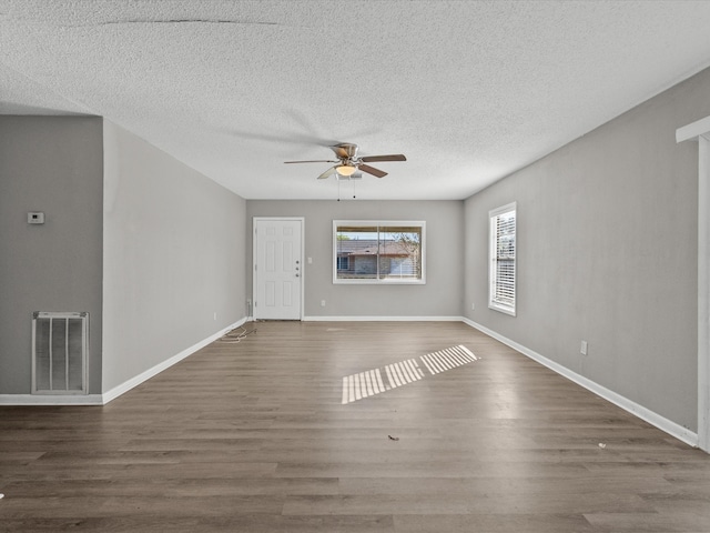 unfurnished living room with dark hardwood / wood-style floors, ceiling fan, and a textured ceiling