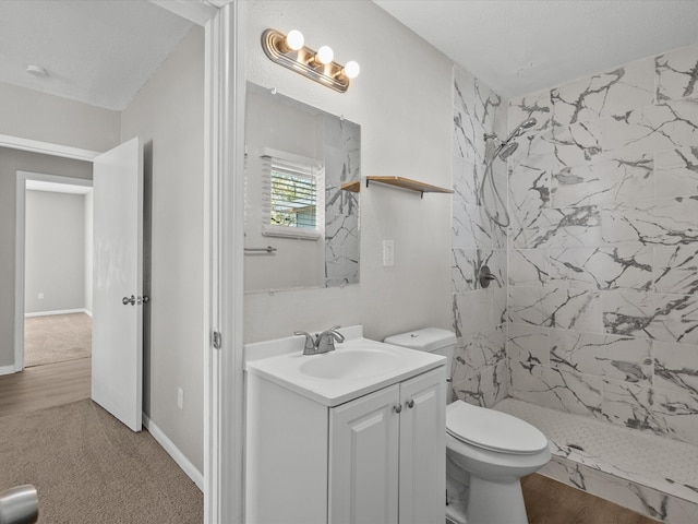 bathroom with tiled shower, hardwood / wood-style floors, vanity, and toilet