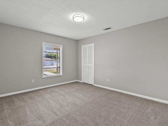 unfurnished room with carpet and a textured ceiling