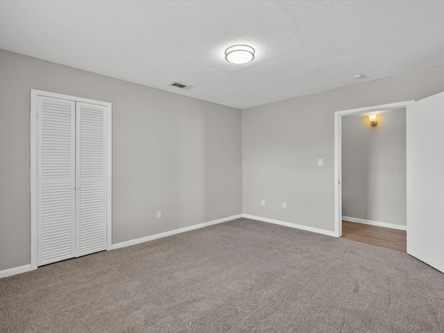 unfurnished bedroom with carpet flooring, a textured ceiling, and a closet