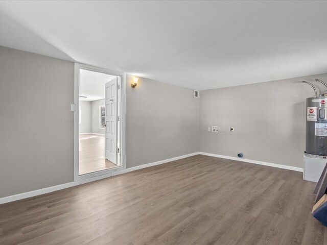 laundry room with electric dryer hookup, wood-type flooring, and water heater