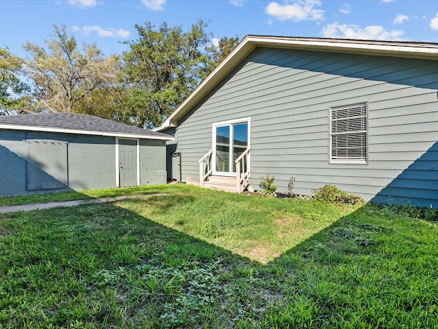 rear view of property featuring a storage unit and a yard