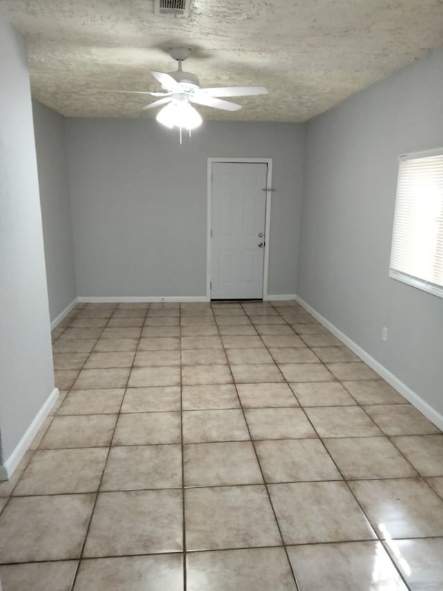 tiled empty room featuring a textured ceiling and ceiling fan