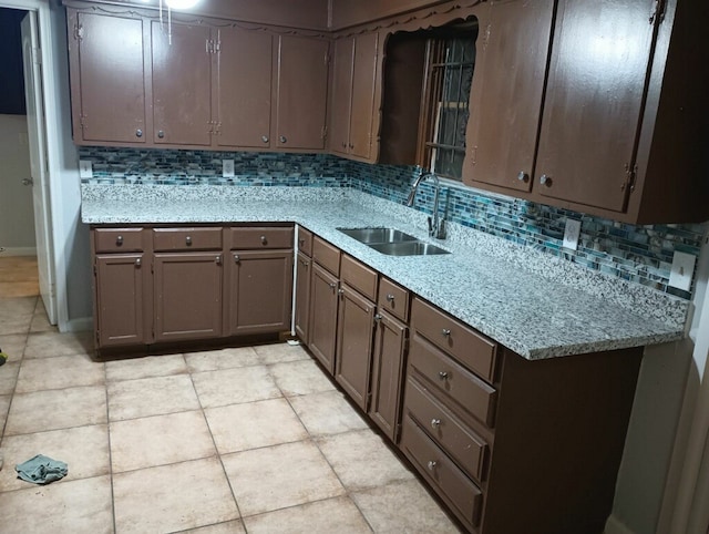 kitchen featuring light tile patterned flooring, decorative backsplash, dark brown cabinets, and sink