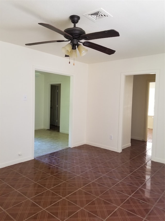 unfurnished room featuring ceiling fan and dark tile patterned flooring