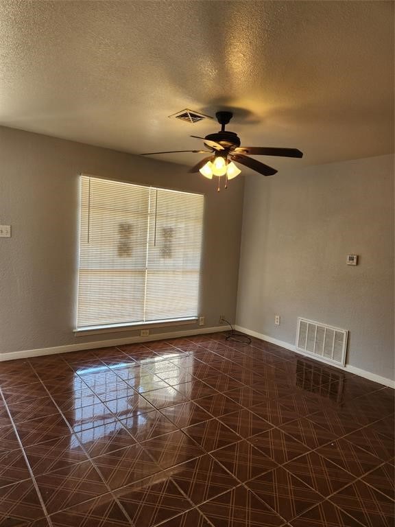 tiled empty room with a textured ceiling and ceiling fan