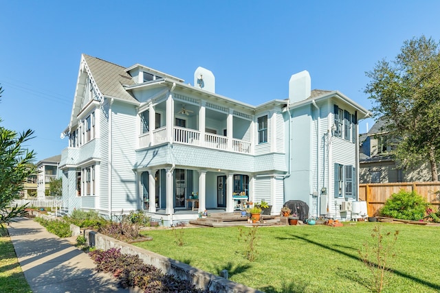 back of house featuring covered porch, a yard, and a balcony