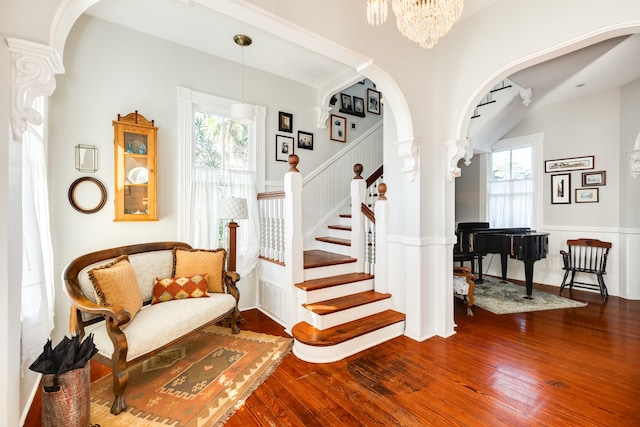 stairs featuring a notable chandelier, plenty of natural light, and wood-type flooring