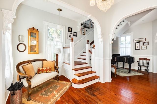 802 16th St, Galveston, TX 77550 - stairway featuring arched walkways, hardwood / wood-style flooring, ornate columns, and a chandelier