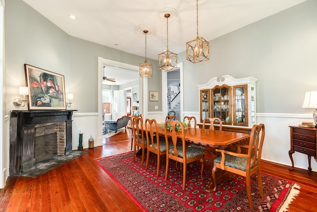 dining room featuring hardwood / wood-style flooring, ceiling fan, and a fireplace