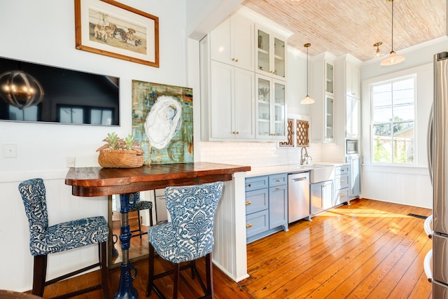 kitchen featuring pendant lighting, white cabinets, light wood-type flooring, wood ceiling, and stainless steel appliances