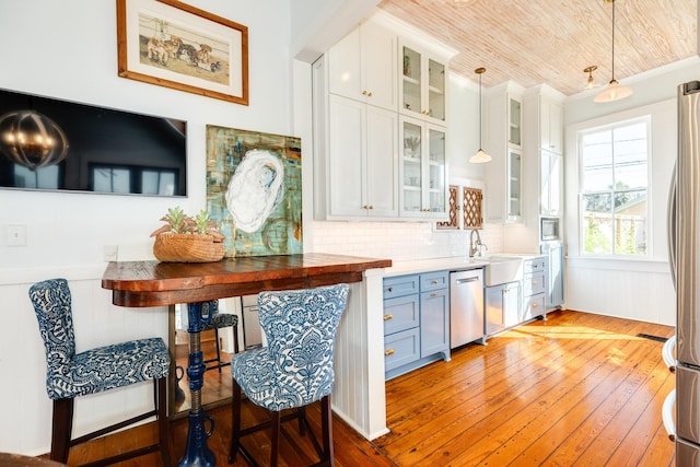 802 16th St, Galveston, TX 77550 - kitchen with stainless steel appliances, light wood-style floors, a sink, decorative light fixtures, and white cabinetry