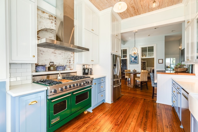 kitchen with wall chimney exhaust hood, stainless steel appliances, dark wood-type flooring, pendant lighting, and white cabinets