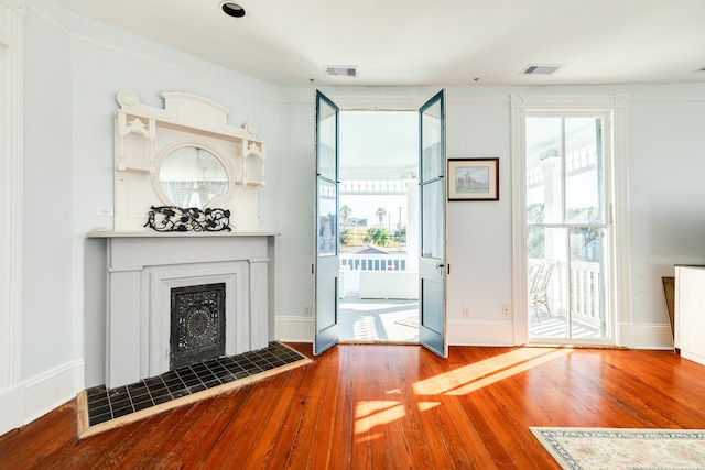 entryway with hardwood / wood-style floors, ornamental molding, and a tile fireplace