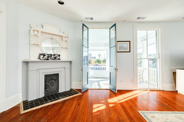 802 16th St, Galveston, TX 77550 - unfurnished living room featuring wood-type flooring, healthy amount of natural light, a tiled fireplace, and baseboards