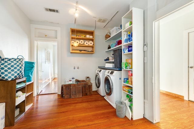 clothes washing area with light hardwood / wood-style flooring and washer and clothes dryer