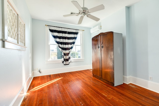 unfurnished bedroom featuring a wall mounted air conditioner, ceiling fan, and dark hardwood / wood-style flooring