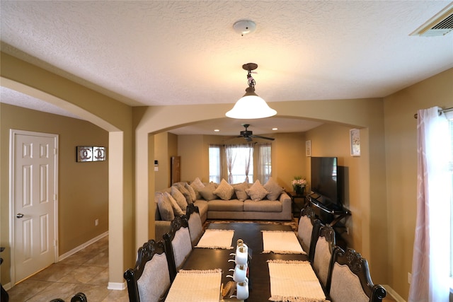 tiled dining room with a textured ceiling and ceiling fan