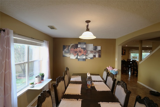 dining room with a textured ceiling and dark tile patterned flooring