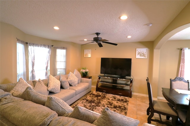 living room with ceiling fan, light tile patterned floors, and a textured ceiling