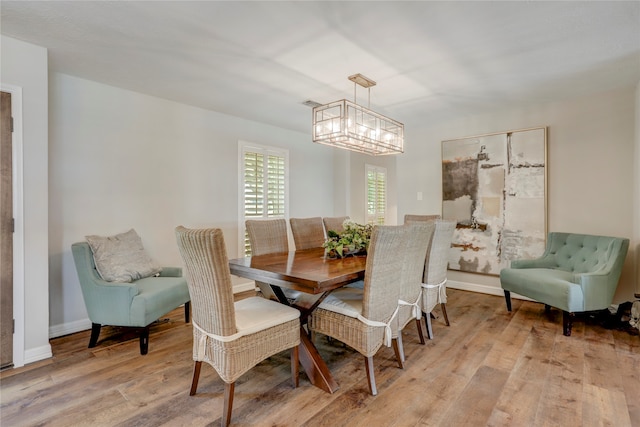 dining space with an inviting chandelier and light hardwood / wood-style flooring