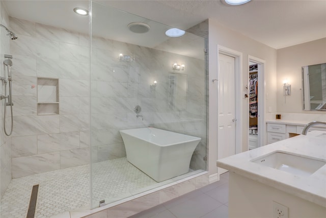 bathroom featuring plus walk in shower, vanity, tile patterned floors, and tile walls